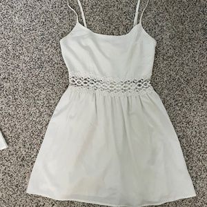Short white dress with lace detailing around waist